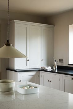 a kitchen with white cabinets and black counter tops, an egg tray on the island