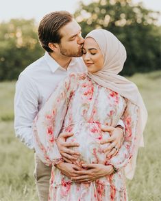 a man and woman kissing each other while standing in a field