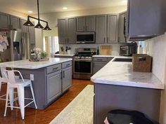 a kitchen with gray cabinets and white counter tops