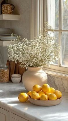 a white bowl filled with lemons sitting on top of a counter next to a window