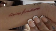 a woman's arm with the word divine feminine written on it, in red ink