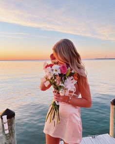 a woman standing on a dock holding flowers