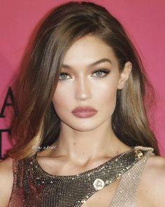 a close up of a person with long hair and wearing a gold dress at an event