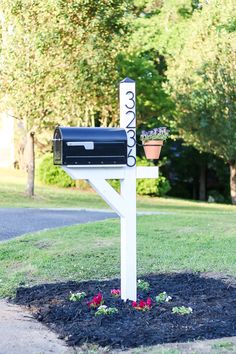 a mailbox in the middle of a flower bed with flowers growing out of it