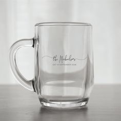 a clear glass mug with the words, the wedding date on it is sitting on a wooden table