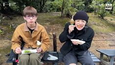 two people sitting on a bench eating food