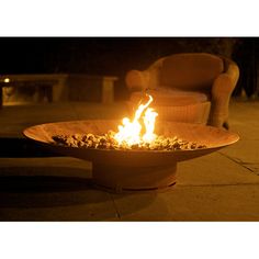 a fire pit sitting on top of a sidewalk next to a chair