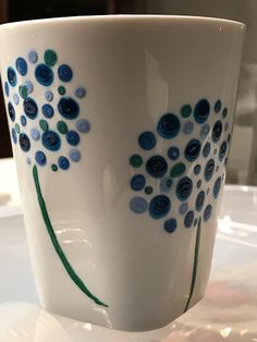 a white cup with blue and green designs on the inside is sitting on a table