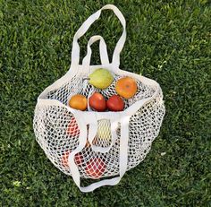 a white bag filled with fruit sitting on top of a lush green grass covered field