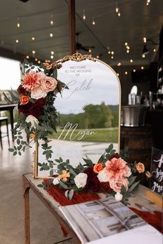 flowers and greenery are arranged on the table for an outdoor wedding ceremony in front of a mirror