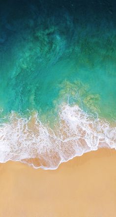 an aerial view of the ocean and beach with waves crashing on it's shore