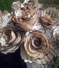 an arrangement of paper flowers sitting on top of a wooden table in front of some grass