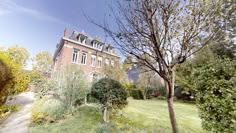 a large brick building sitting on top of a lush green field next to a tree