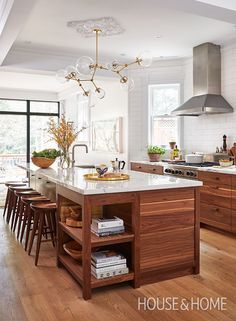 a kitchen with wooden floors and an island in front of a stove top oven surrounded by chairs