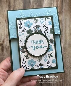 someone holding up a thank you card with blue flowers on the front and green leaves on the back