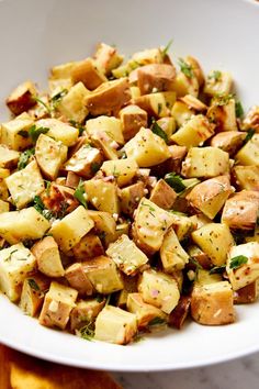 a white bowl filled with potatoes and herbs