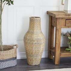 a vase sitting next to a table with a plant in it