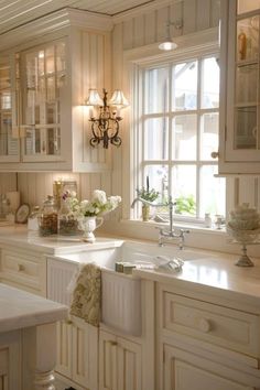 a kitchen filled with lots of white cabinets and counter top space next to a window