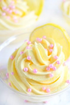 cupcakes with white frosting and pink sprinkles in a glass bowl