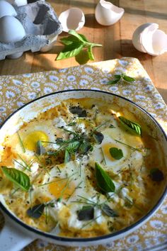 an egg dish with herbs and eggs in the background