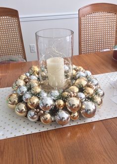 a candle is sitting on top of a table with christmas ornaments and balls around it