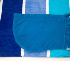 a blue and white striped towel laying on top of a bed next to a pillow