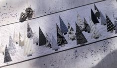 a quilted wall hanging with black and white christmas trees on it's sides