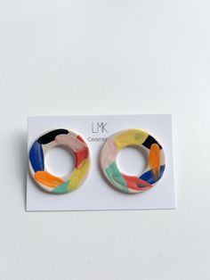 pair of colorful earrings on white card with black and orange lettering that reads lmk collective