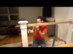 a man in an orange shirt is holding a drill and looking at the camera while working on a wooden rail