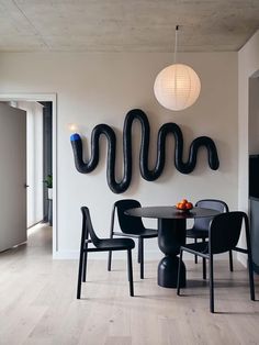 a dining room table with black chairs and an inflatable snake on the wall