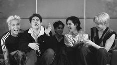 four young men sitting on top of a couch laughing and having fun with each other