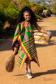 a woman walking down a dirt road holding a basket