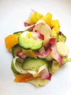 a white plate topped with cucumbers and other vegetables