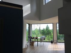 an open living room with wood floors and large windows overlooking the trees outside in front of it