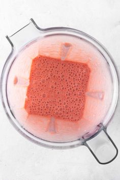 a blender filled with orange liquid on top of a white counter