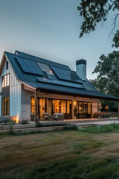 a modern house with solar panels on the roof and large windows in front of it