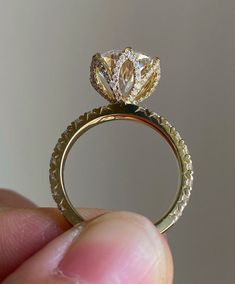 a close up of a person's hand holding a ring with a diamond on it