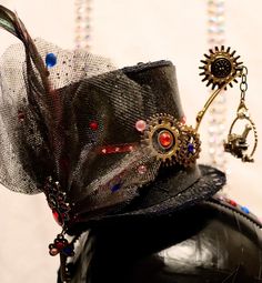 "🎩 Small Black Top Hat on a Headband, adorned with gears, a small \"mechanical bird\" perched on a twisted swing, a colored peacock broach with key, ribbon, colorful gems, feathers &  toole  My Punkadelic Headbands are One of a kind Frilly, Feathery, Fancy, Flowy & Funtastic and is sure to Punky up your Funky as you Gear up for any Event or Party!  ⚙️Every Punkadelic Item is One-Of-A-Kind, Handcrafted, Unique & Eclectic. Each Imperfectly Perfect Creations is Made with ❤️ &  My 🤲🏻.   🗝Please Mechanical Bird, Steampunk Top, Surprise Birthday Gifts, Steampunk Top Hat, Imperfectly Perfect, Black Top Hat, Bird Perch, Costume Hats, Top Hat