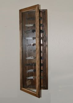 a wooden case with several glasses in it on the wall next to a white wall