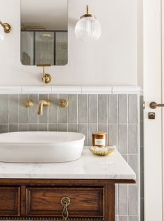 a bathroom sink sitting under a mirror next to a wooden cabinet with two lights on it