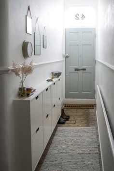 a hallway with white cabinets and a gray door