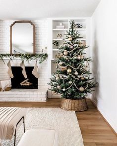 a living room decorated for christmas with a tree in the corner and stockings on the fireplace