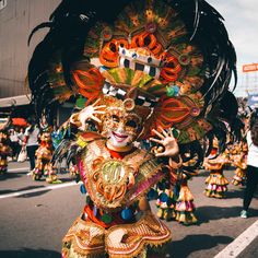 an elaborately dressed woman in the street during a carnival parade on a sunny day