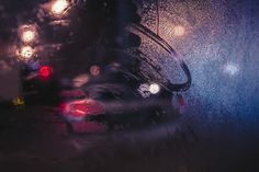 a car is driving down the street in the rain at night with its lights on