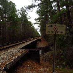 there is a no trespassing sign on the side of the tracks in the woods