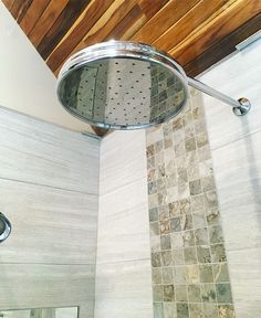 a shower head in a tiled bathroom with wood ceiling