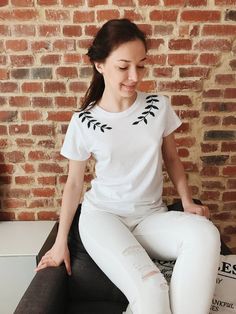 a woman sitting on top of a bench wearing white pants and a t - shirt