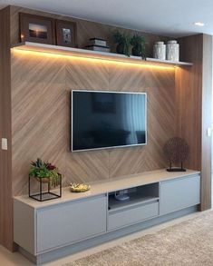 a living room with a large television mounted on the wall and some plants in vases