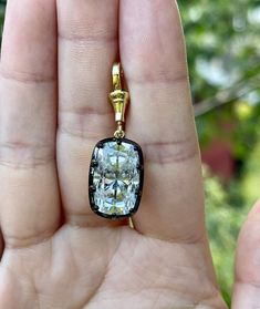 a person holding up a pendant with a diamond in it