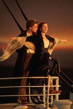 a man and woman standing on top of a boat